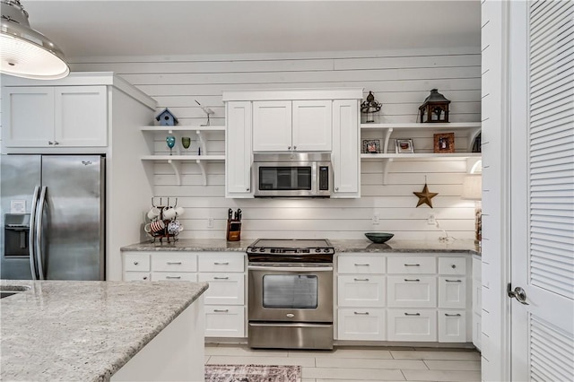 kitchen with open shelves, white cabinets, stainless steel appliances, and light stone counters