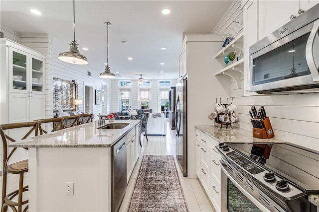 kitchen with white cabinets, appliances with stainless steel finishes, open floor plan, and a sink