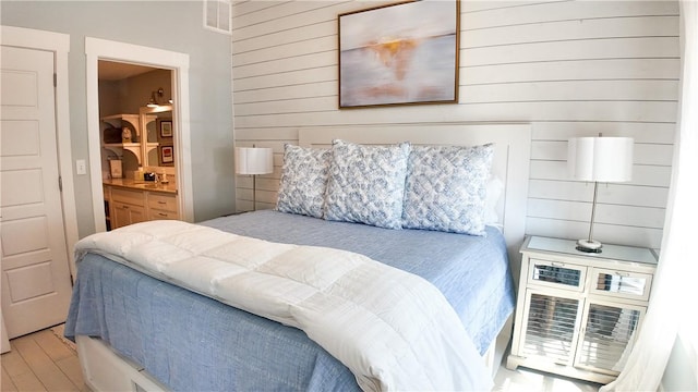 bedroom with wood walls, wood finished floors, and connected bathroom