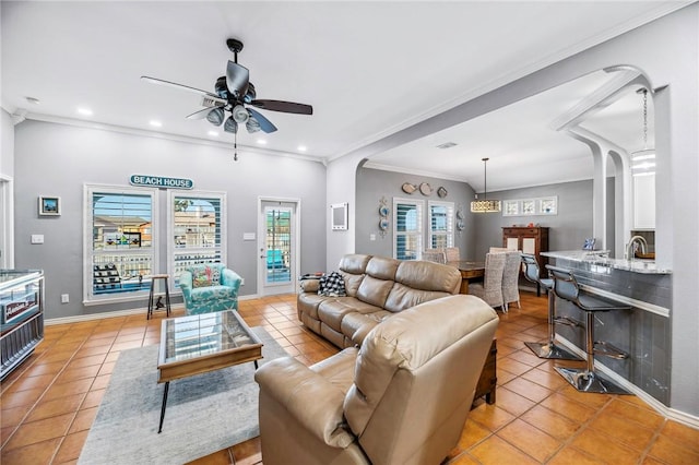 living area featuring light tile patterned floors, recessed lighting, ornamental molding, ceiling fan, and baseboards