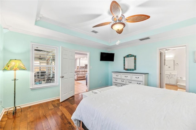 bedroom featuring ornamental molding, wood-type flooring, a raised ceiling, and visible vents