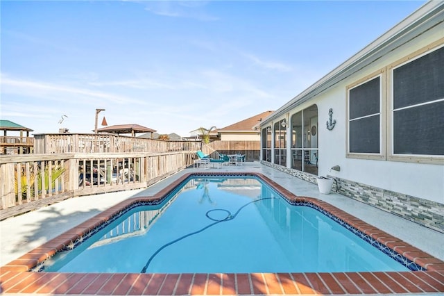 view of swimming pool with a fenced in pool, a sunroom, a patio area, and a fenced backyard