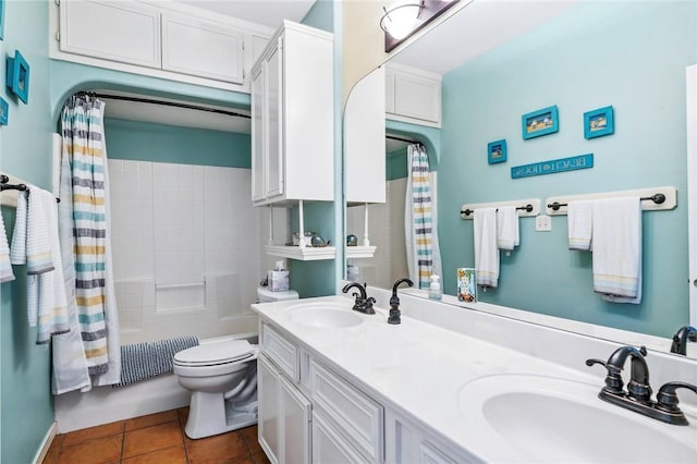 bathroom with double vanity, a sink, toilet, and tile patterned floors