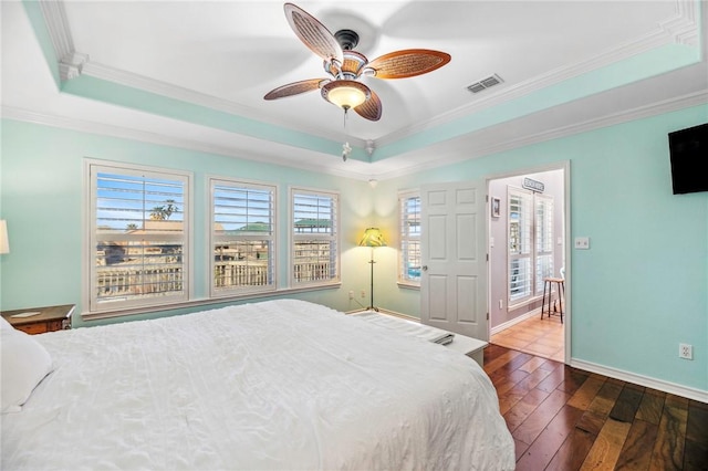 bedroom with baseboards, visible vents, a raised ceiling, dark wood-style flooring, and crown molding