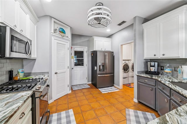 kitchen featuring visible vents, backsplash, appliances with stainless steel finishes, white cabinetry, and independent washer and dryer