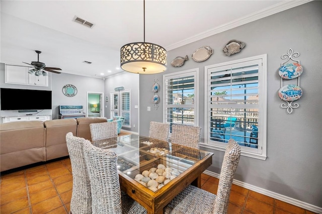 tiled dining room with ornamental molding, visible vents, baseboards, and a ceiling fan