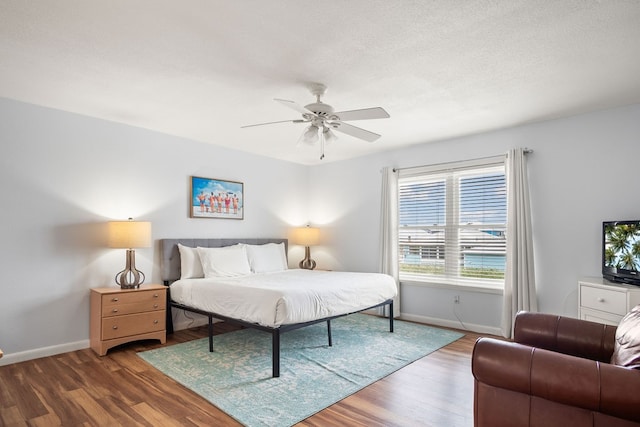 bedroom featuring ceiling fan, a textured ceiling, and dark hardwood / wood-style flooring