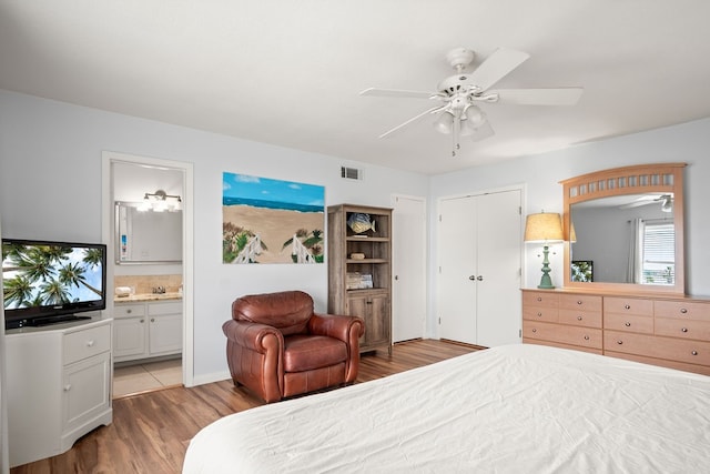 bedroom with ensuite bathroom, light wood-type flooring, and ceiling fan