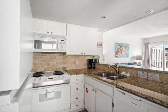 kitchen featuring dark stone countertops, white cabinetry, white appliances, and sink