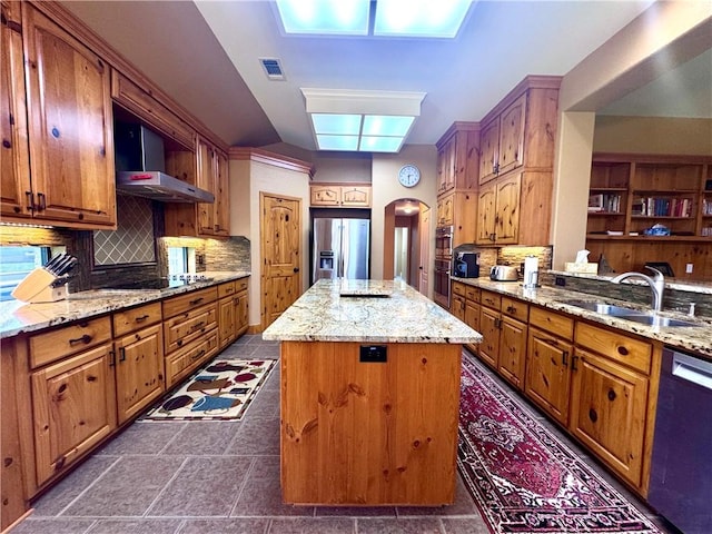 7605 Bayonne Dr, Corpus Christi, TX 78414 - kitchen featuring appliances with stainless steel finishes, wall chimney exhaust hood, arched walkways, a center island, and light stone counters