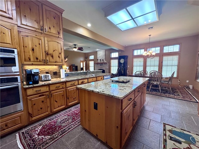 7605 Bayonne Dr, Corpus Christi, TX 78414 - kitchen featuring a chandelier, a center island, plenty of natural light, recessed lighting, and brown cabinetry