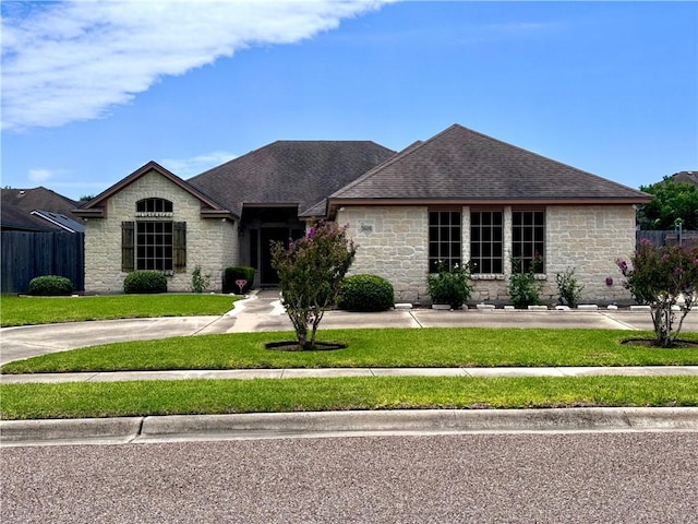 7605 Bayonne Dr, Corpus Christi, TX 78414 - view of front facade with stone siding, a front lawn, and roof with shingles