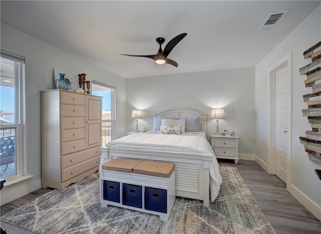 bedroom with multiple windows, wood-type flooring, and ceiling fan