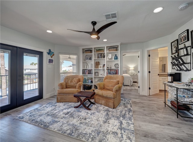 living room with french doors, ceiling fan, and light wood-type flooring