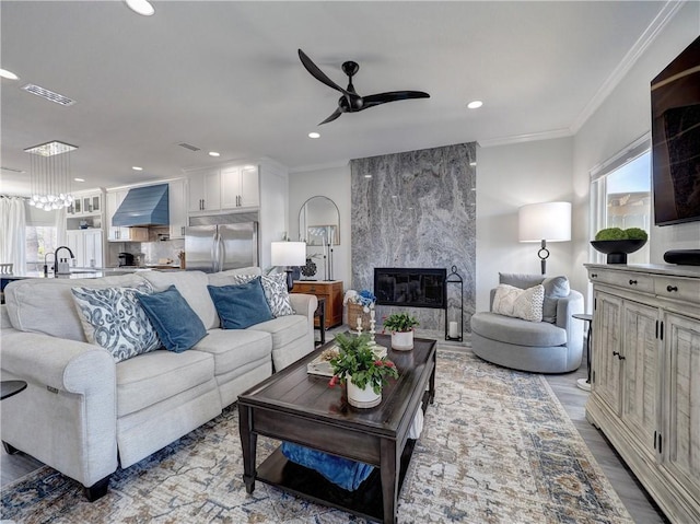 living room featuring crown molding, ceiling fan, and a fireplace