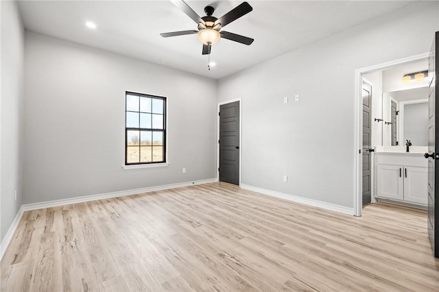 unfurnished bedroom featuring a ceiling fan, baseboards, ensuite bath, and light wood finished floors