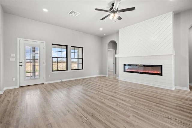 unfurnished living room with light wood-style floors, visible vents, and a glass covered fireplace