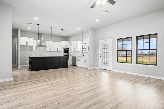 kitchen with appliances with stainless steel finishes, open floor plan, visible vents, and wall chimney range hood