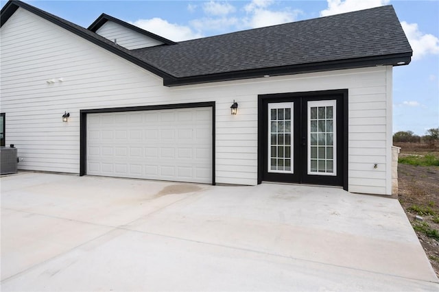 garage with central air condition unit and concrete driveway