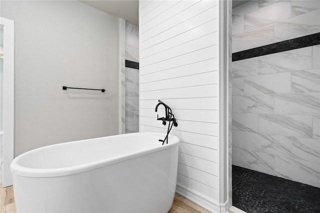 full bathroom with a freestanding bath, tiled shower, and wood finished floors