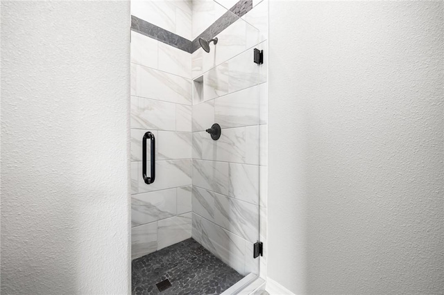 full bathroom featuring a stall shower and a textured wall