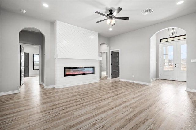 unfurnished living room with visible vents, a ceiling fan, a glass covered fireplace, light wood-style flooring, and recessed lighting