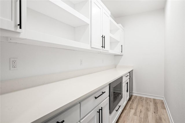 bar with baseboards, light wood-style floors, and built in microwave