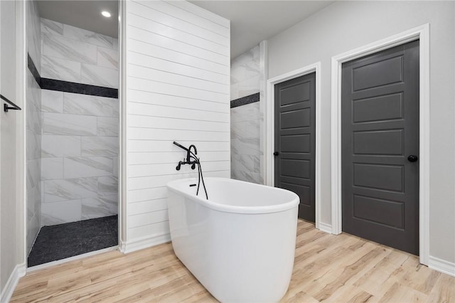 bathroom featuring a freestanding tub, a walk in shower, wood finished floors, and recessed lighting