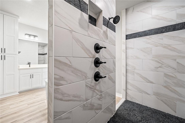 full bath with a tile shower and vanity