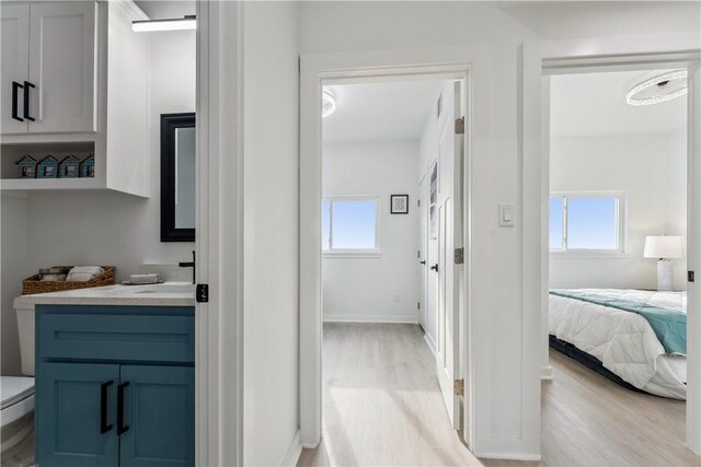 ensuite bathroom featuring vanity, wood finished floors, toilet, baseboards, and ensuite bath