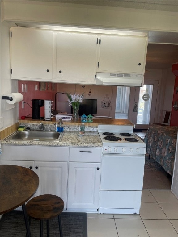 kitchen featuring white cabinetry, light tile patterned flooring, sink, and white stove