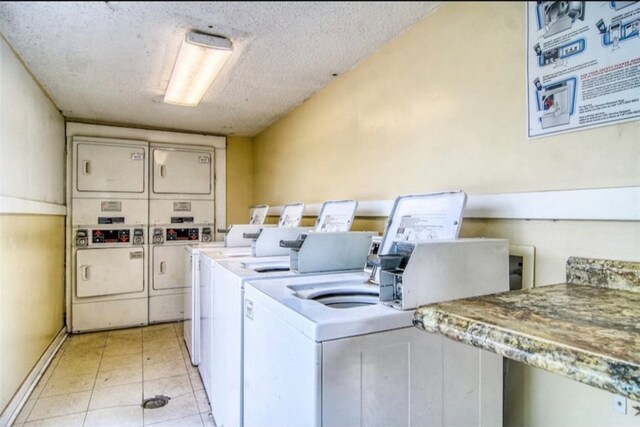 washroom with stacked washing maching and dryer, a textured ceiling, and light tile patterned floors