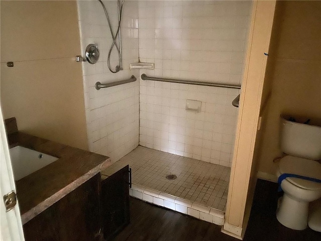 bathroom featuring hardwood / wood-style floors, vanity, a tile shower, and toilet