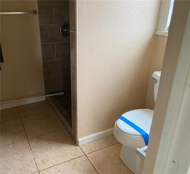 bathroom featuring tiled shower, tile patterned floors, and toilet