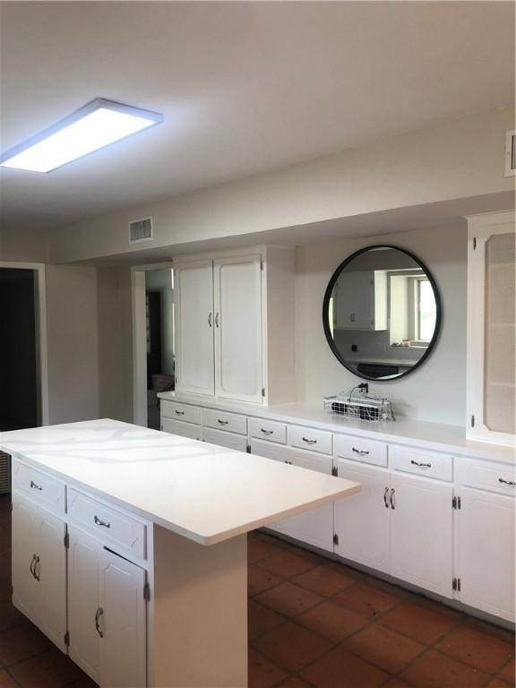 kitchen with white cabinetry, a center island, and dark tile patterned flooring