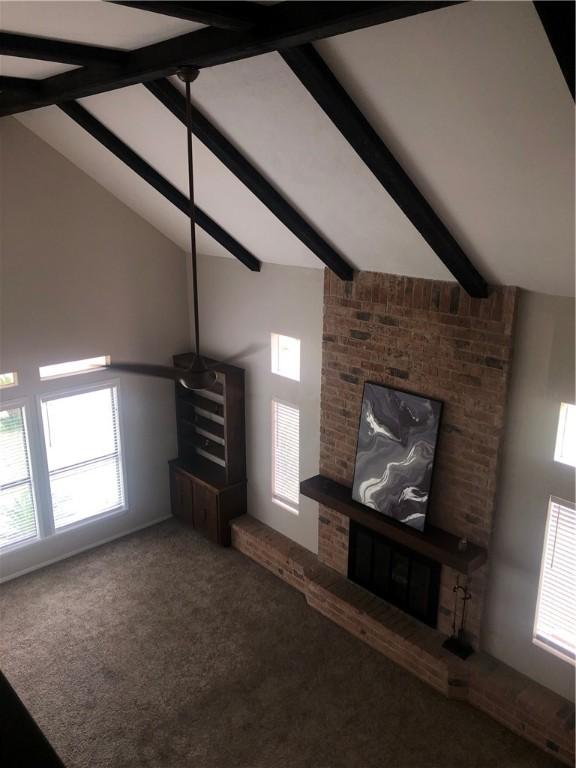 unfurnished living room featuring beamed ceiling, high vaulted ceiling, and carpet