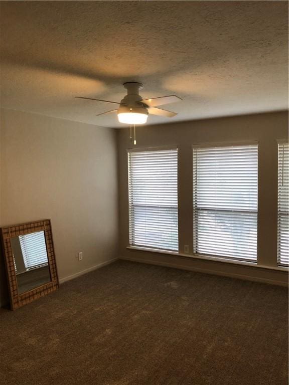 unfurnished room featuring ceiling fan, a textured ceiling, and dark carpet