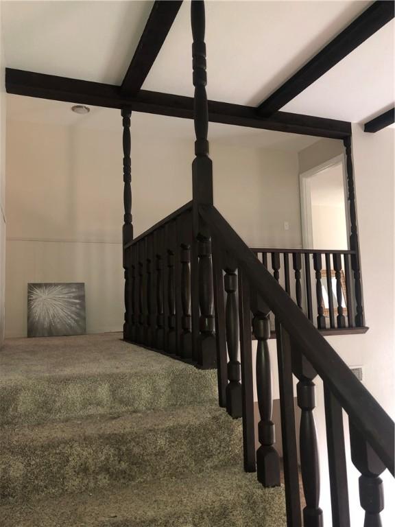 stairway featuring beamed ceiling and carpet flooring