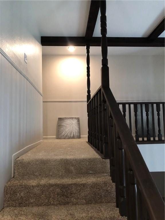 staircase with carpet floors and beamed ceiling