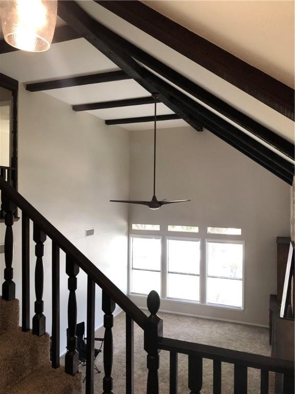 stairway with vaulted ceiling with beams and carpet floors