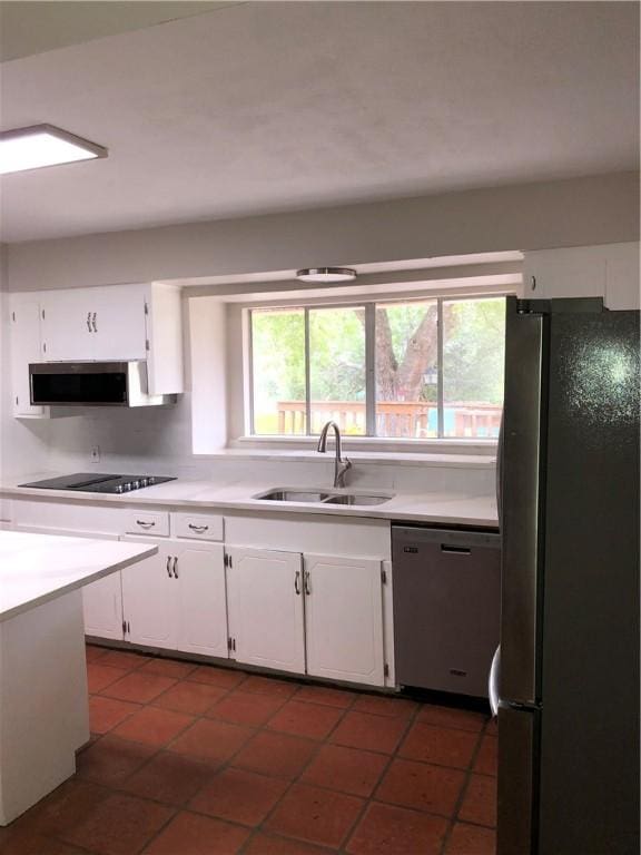 kitchen with appliances with stainless steel finishes, sink, white cabinets, and dark tile patterned flooring