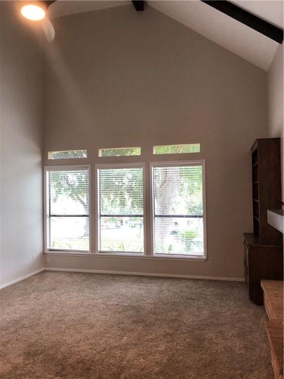 unfurnished living room featuring beam ceiling, high vaulted ceiling, and carpet