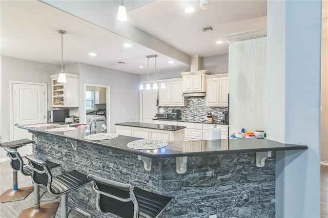 6705 Empire State Dr, Corpus Christi, TX 78414 - kitchen featuring dark countertops, a kitchen island, tasteful backsplash, a breakfast bar area, and recessed lighting