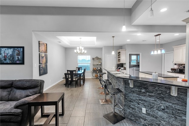 6705 Empire State Dr, Corpus Christi, TX 78414 - kitchen with dark countertops, a tray ceiling, hanging light fixtures, recessed lighting, and white cabinets