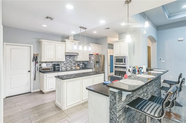 6705 Empire State Dr, Corpus Christi, TX 78414 - kitchen with stainless steel appliances, a kitchen island, arched walkways, a kitchen breakfast bar, and decorative backsplash
