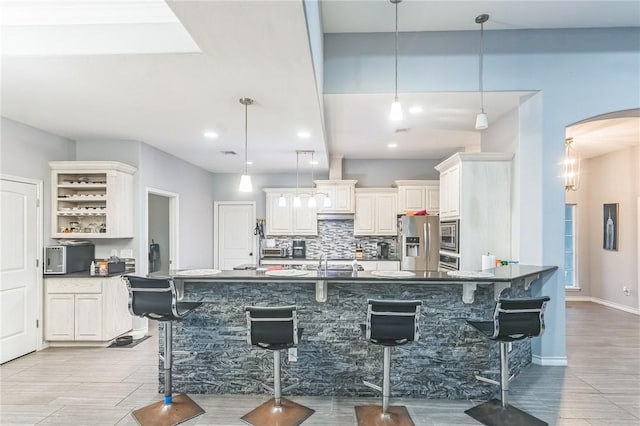 6705 Empire State Dr, Corpus Christi, TX 78414 - kitchen featuring appliances with stainless steel finishes, dark countertops, arched walkways, a breakfast bar, and backsplash