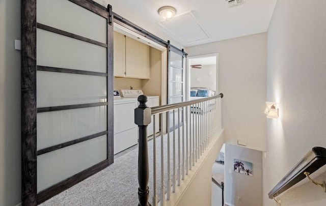 corridor featuring a barn door, visible vents, carpet, washer and dryer, and an upstairs landing