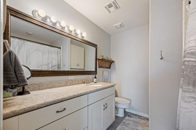 bathroom with toilet, vanity, visible vents, and baseboards