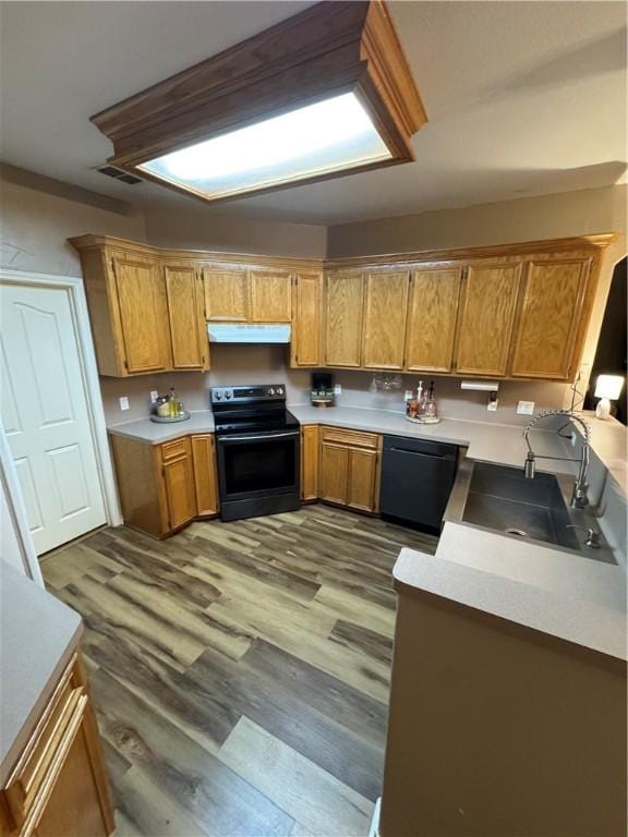 kitchen with sink, black appliances, and hardwood / wood-style floors