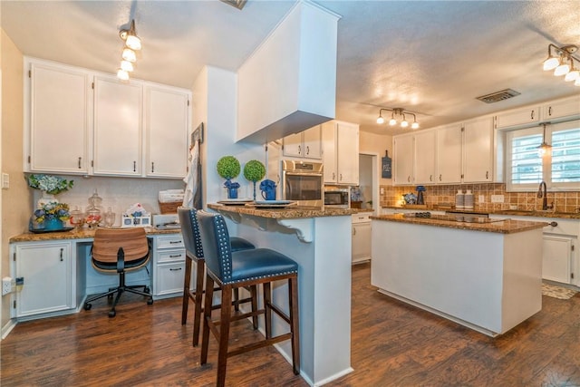 kitchen with dark stone countertops, white cabinetry, and a kitchen island